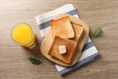 Photo of Delicious toasted bread slices with butter served on wooden table, flat lay