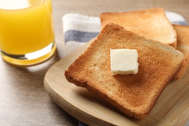 Photo of Delicious toasted bread slices with butter served on wooden table, closeup