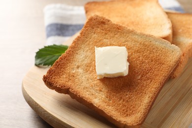 Photo of Delicious toasted bread slices with butter on table, closeup