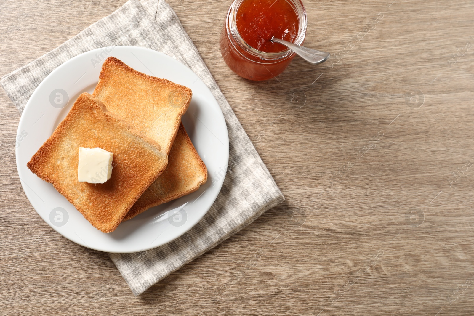 Photo of Delicious toasted bread slices with butter and jam on wooden table, flat lay. Space for text