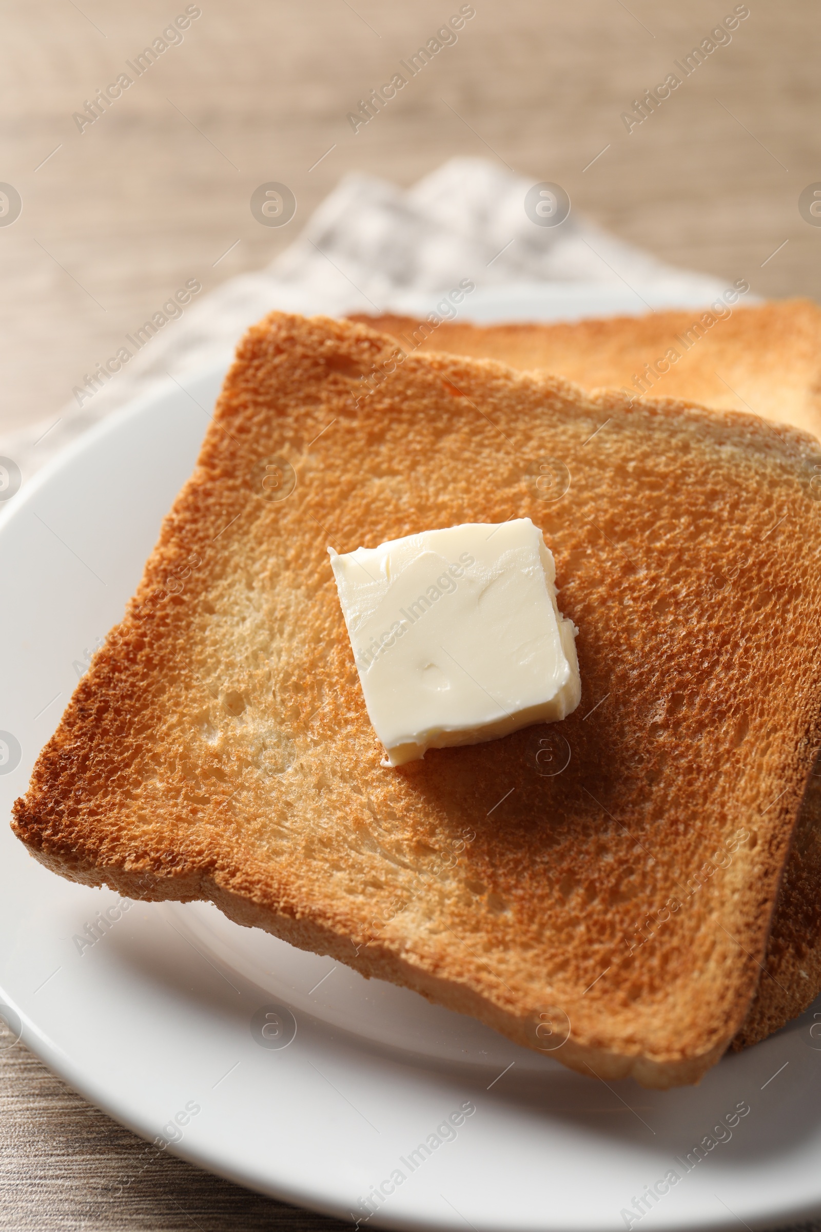 Photo of Delicious toasted bread slices with butter on table, closeup