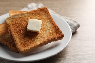 Delicious toasted bread slices with butter on wooden table, closeup