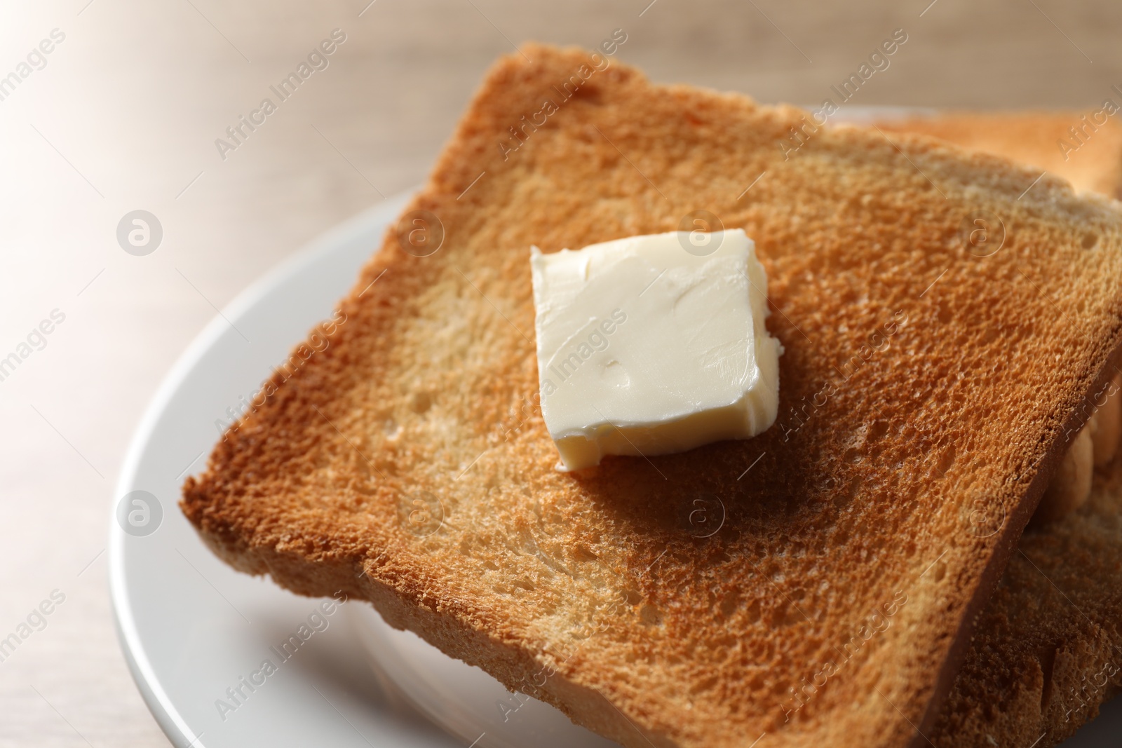 Photo of Delicious toasted bread slices with butter on table, closeup