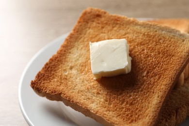 Photo of Delicious toasted bread slices with butter on table, closeup