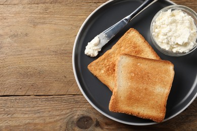 Photo of Delicious toasted bread slices with cream cheese and knife on wooden table, top view. Space for text