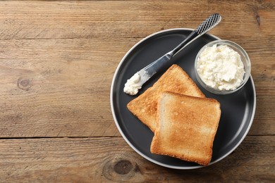 Photo of Delicious toasted bread slices with cream cheese and knife on wooden table, top view. Space for text