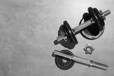 Photo of Barbell and parts of one on grey floor, flat lay. Space for text