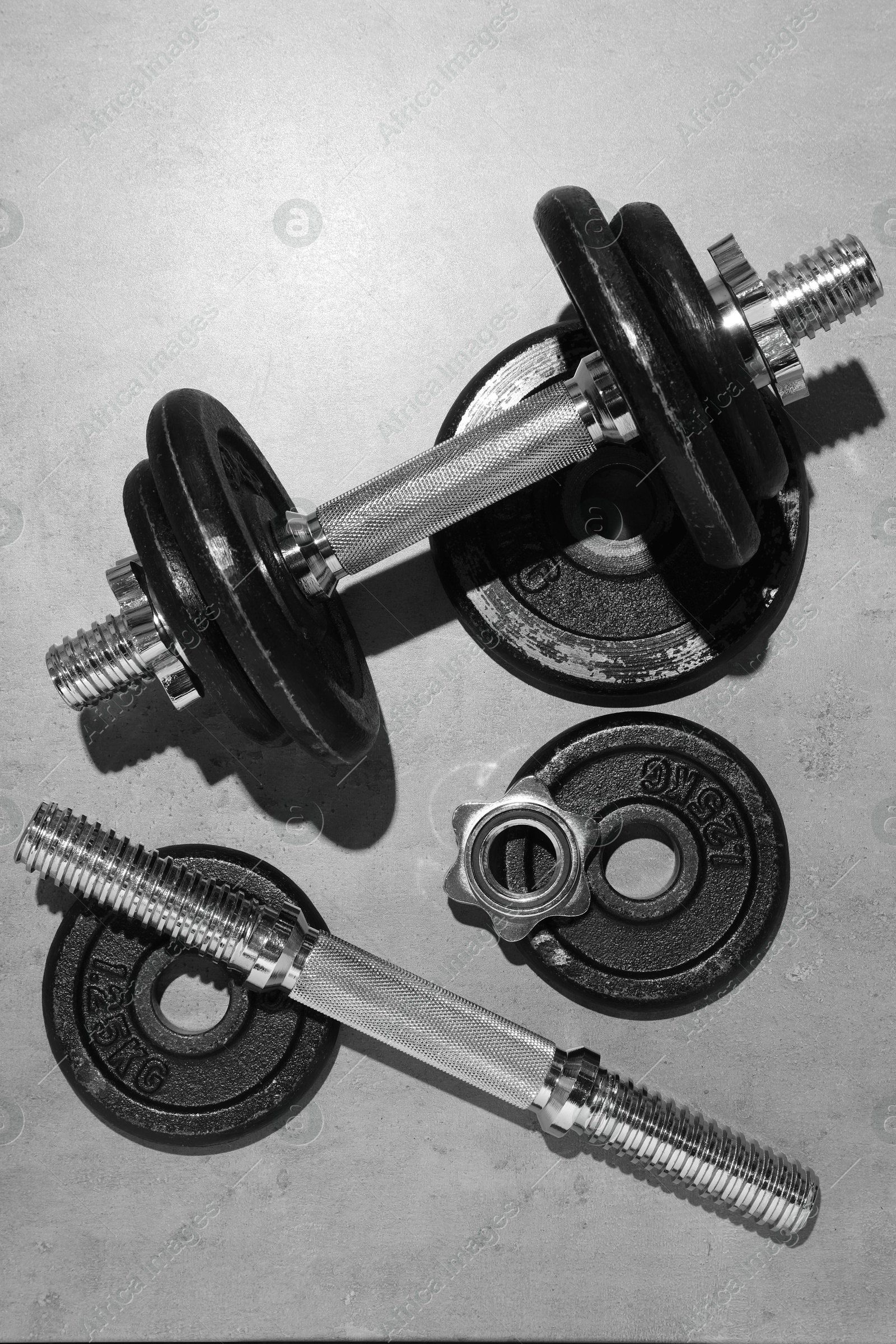 Photo of Barbell and parts of one on grey floor, flat lay