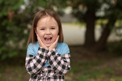 Photo of Portrait of emotional little girl outdoors, space for text