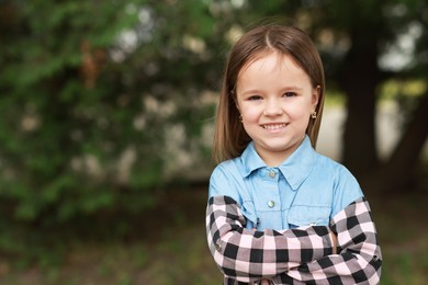 Photo of Portrait of happy little girl with crossed arms outdoors space for text