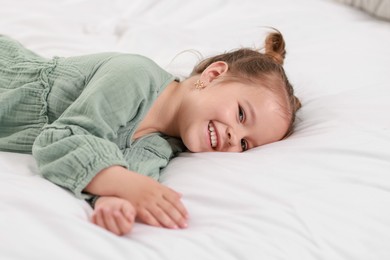 Portrait of happy little girl on bed