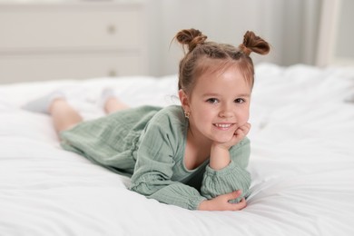 Portrait of happy little girl on bed at home