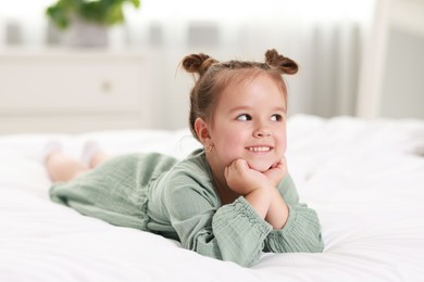 Portrait of happy little girl on bed at home