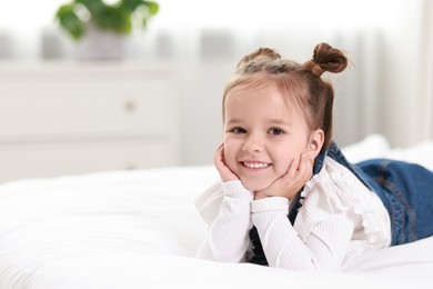 Photo of Portrait of happy little girl on bed indoors, space for text