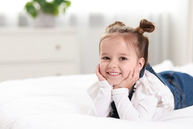 Portrait of happy little girl on bed indoors, space for text