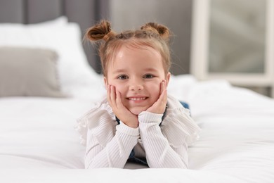 Portrait of happy little girl on bed indoors