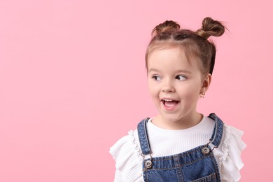 Photo of Portrait of emotional little girl on pink background, space for text
