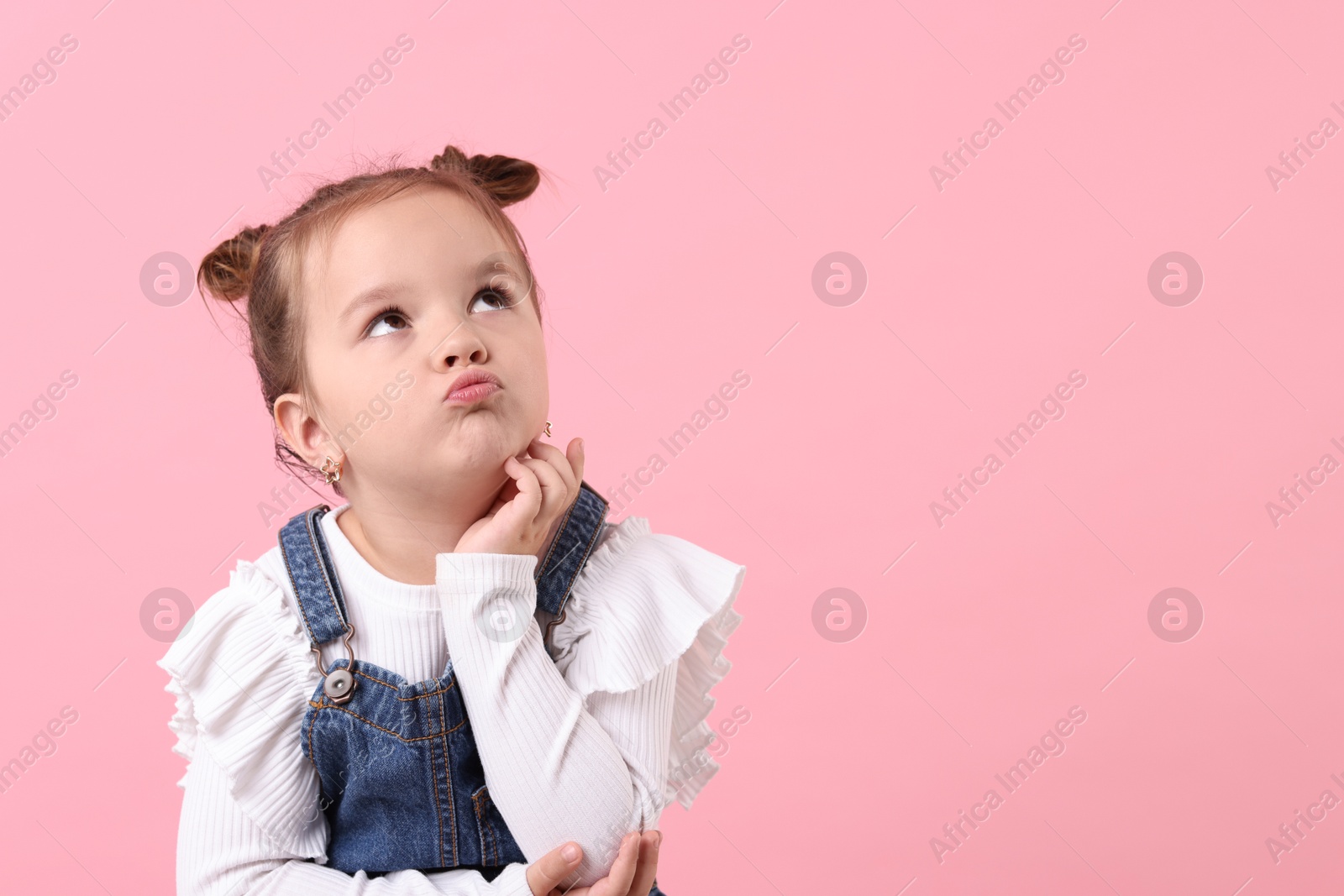 Photo of Portrait of cute little girl on pink background, space for text