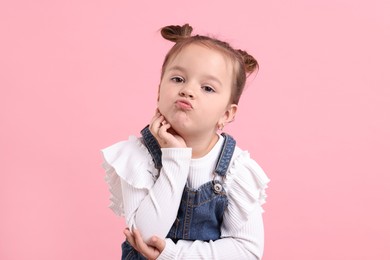 Portrait of cute little girl on pink background