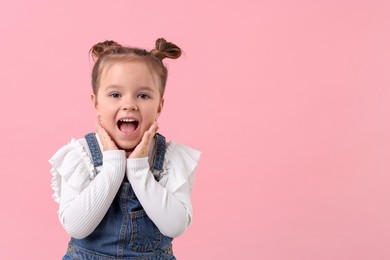 Photo of Portrait of emotional little girl on pink background, space for text