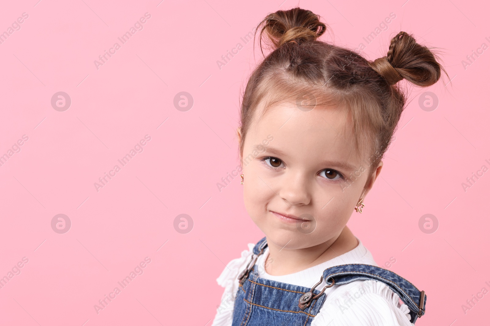 Photo of Portrait of cute little girl on pink background, space for text