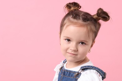 Photo of Portrait of cute little girl on pink background, space for text