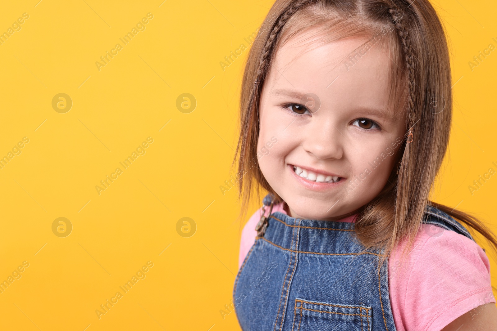 Photo of Portrait of happy little girl on orange background, space for text