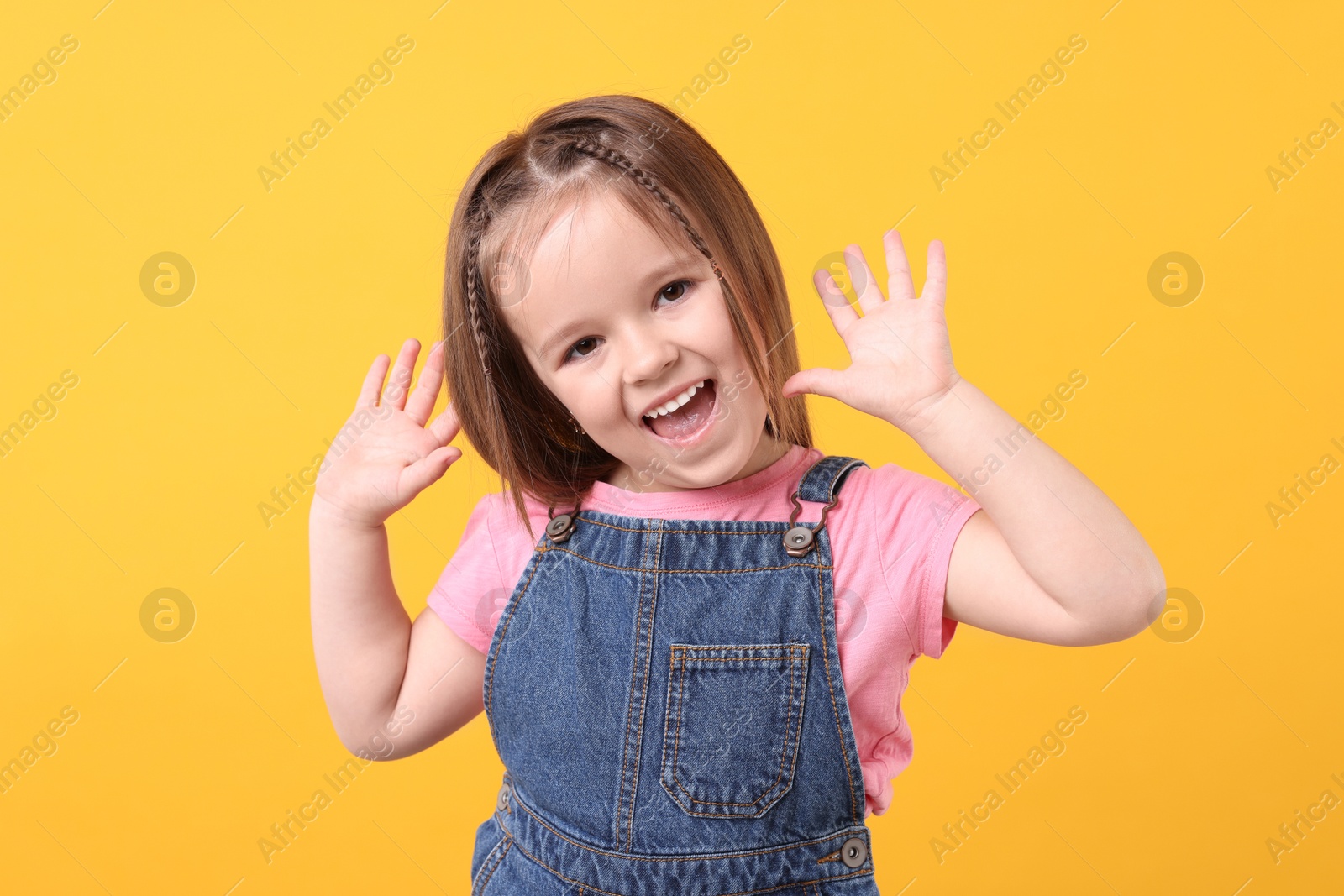 Photo of Portrait of emotional little girl on orange background