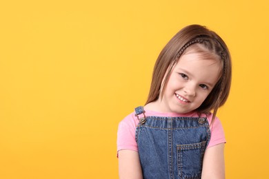 Portrait of happy little girl on orange background, space for text