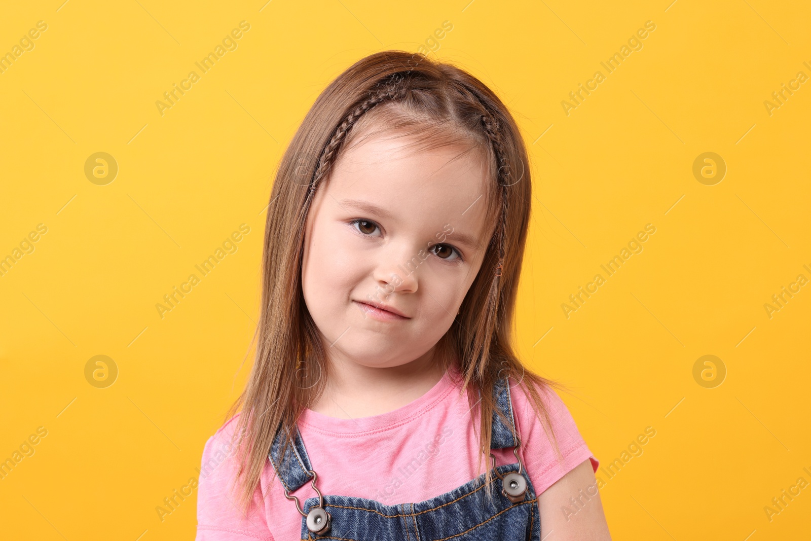 Photo of Portrait of cute little girl on orange background