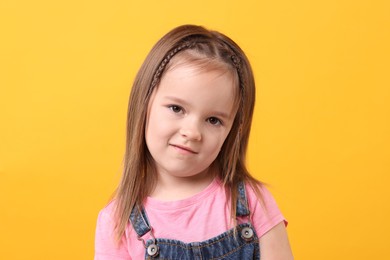 Portrait of cute little girl on orange background