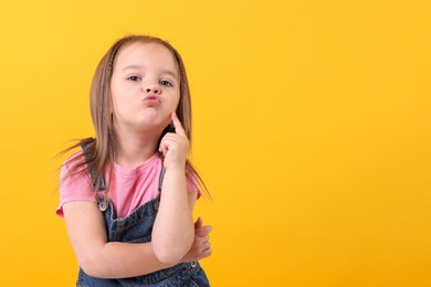 Portrait of cute little girl on orange background, space for text