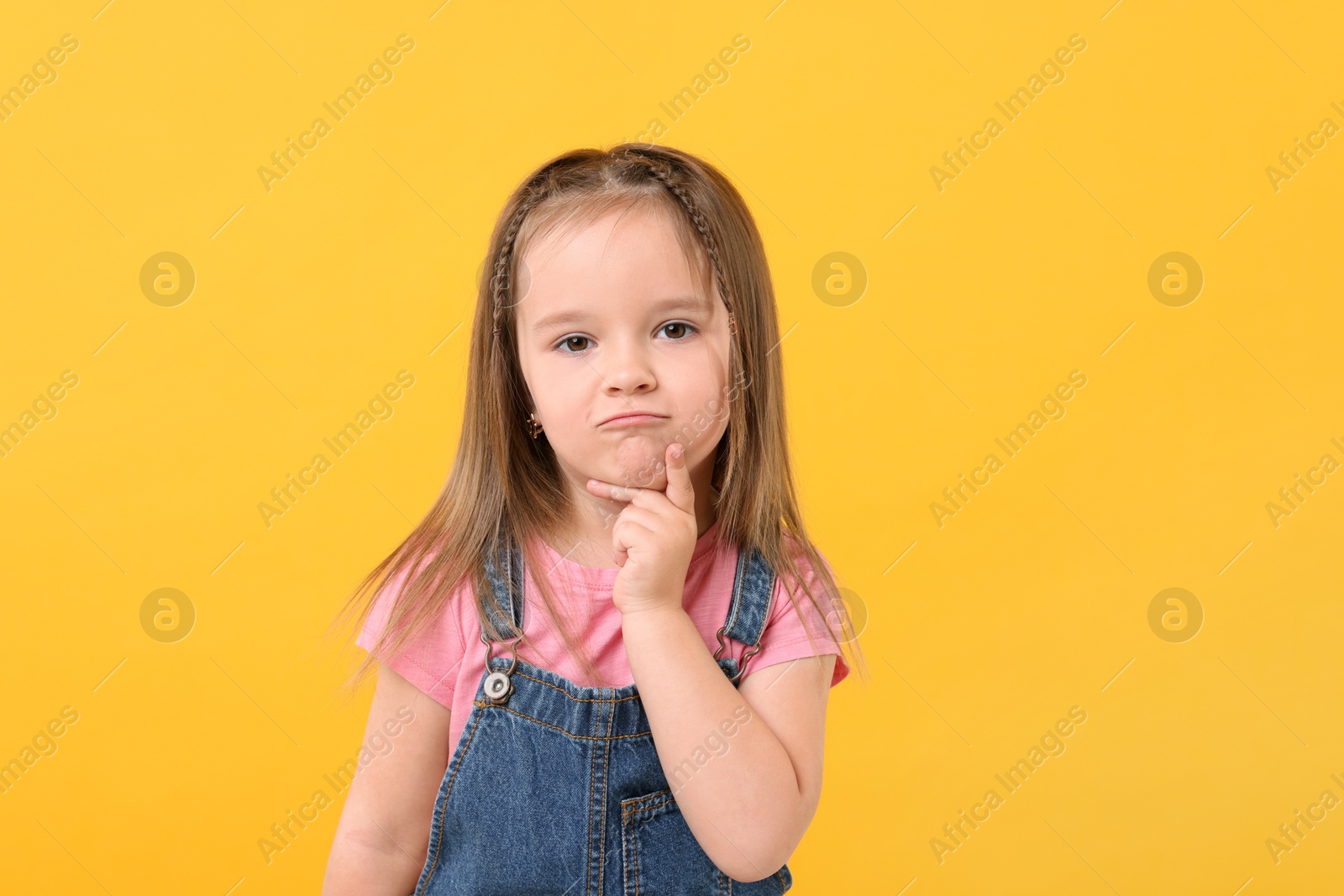 Photo of Portrait of cute little girl on orange background