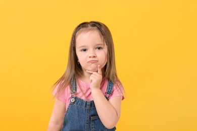 Photo of Portrait of cute little girl on orange background