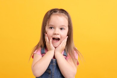 Photo of Portrait of emotional little girl on orange background