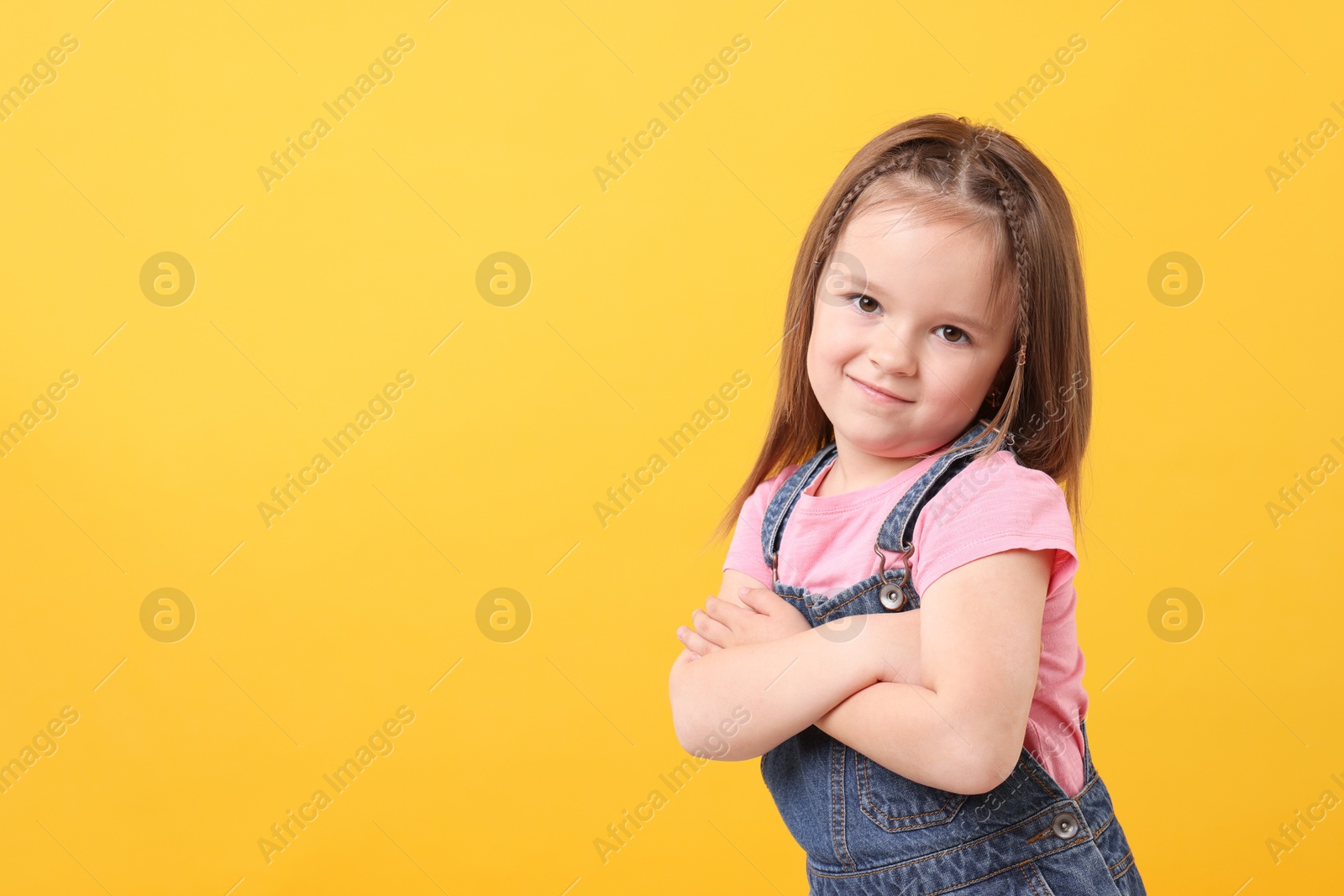 Photo of Portrait of cute little girl on orange background, space for text