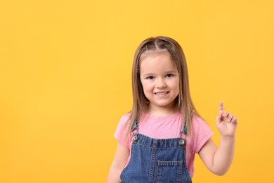 Portrait of happy little girl on orange background, space for text