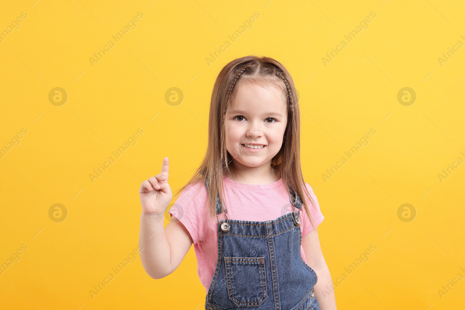 Photo of Portrait of happy little girl on orange background