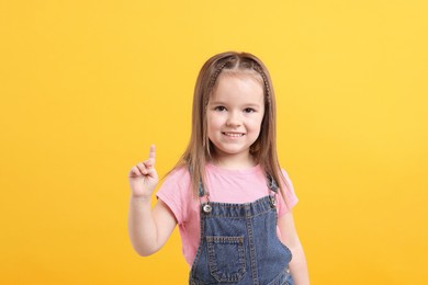 Portrait of happy little girl on orange background