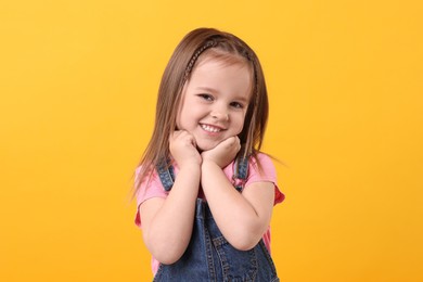 Photo of Portrait of happy little girl on orange background