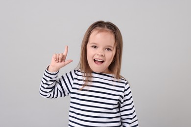 Photo of Portrait of emotional little girl pointing at something on grey background