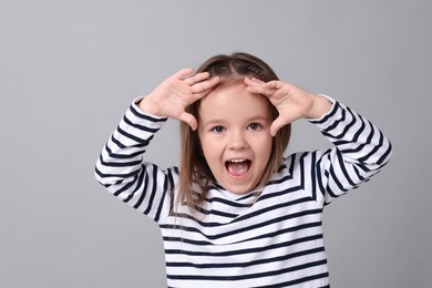 Portrait of emotional little girl on grey background