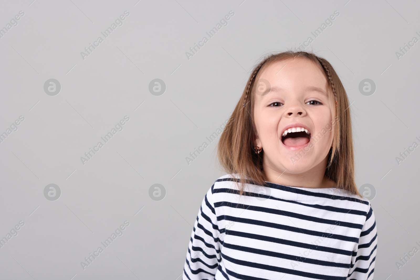 Photo of Portrait of emotional little girl on grey background, space for text