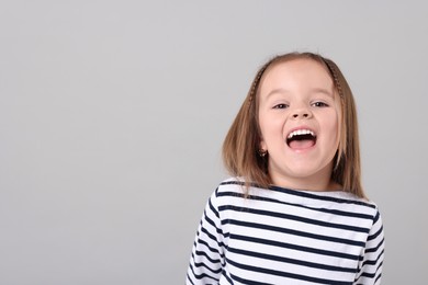 Photo of Portrait of emotional little girl on grey background, space for text