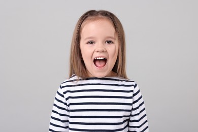 Portrait of emotional little girl on grey background