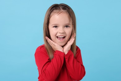 Photo of Portrait of happy little girl on light blue background