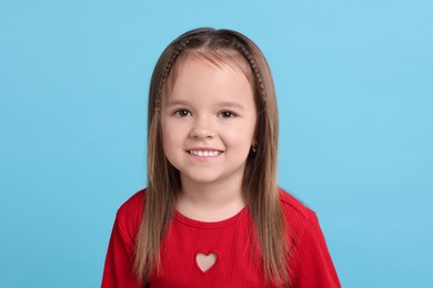 Portrait of happy little girl on light blue background