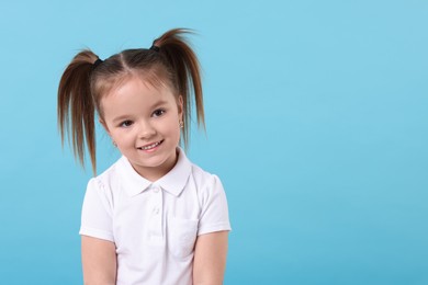 Photo of Portrait of happy little girl on light blue background, space for text