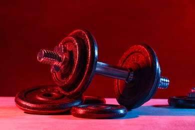 Photo of Barbell and parts of one on table in color lights