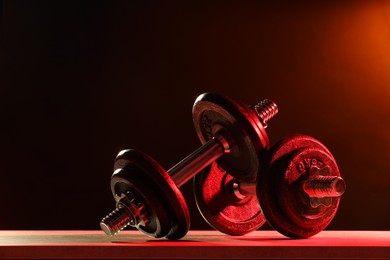 Two barbells on table in color lights. Space for text